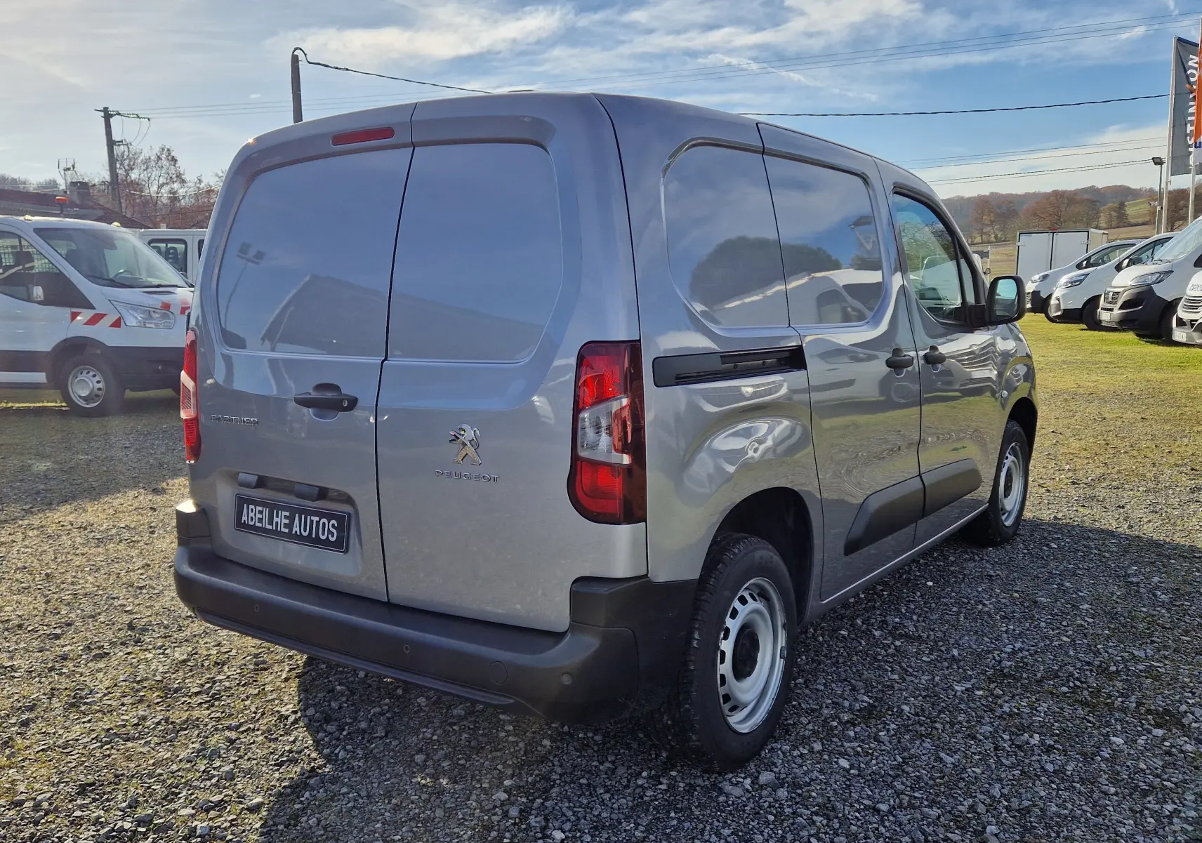 Vue 3/4 arrière droite d'un Peugeot Partner gris Artense 2021, fourgon utilitaire avec portes arrière battantes.