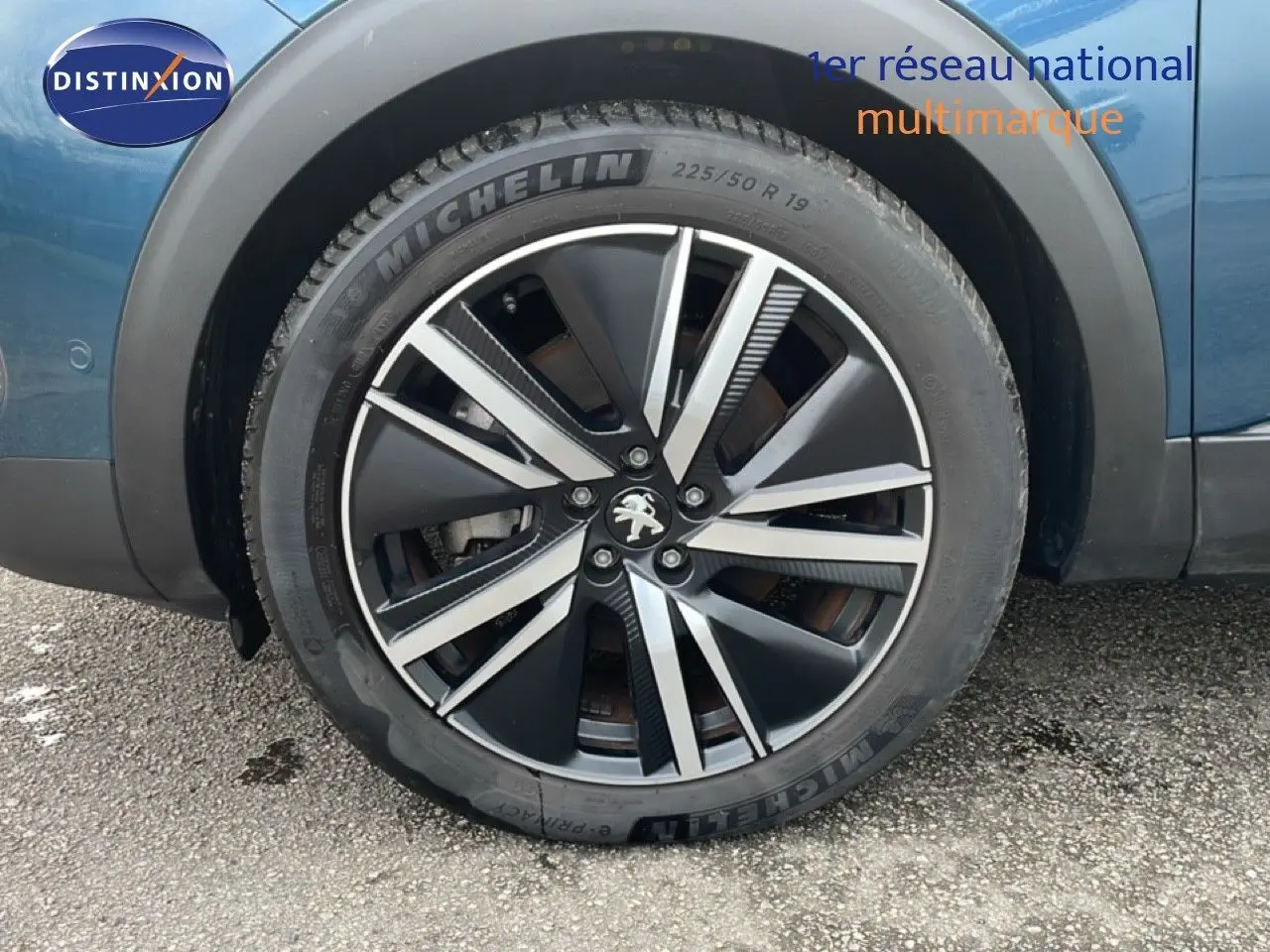 Gros plan sur la roue avant droite du Peugeot 3008 bleu Célèbes Métal avec jante alliage noire et argentée.