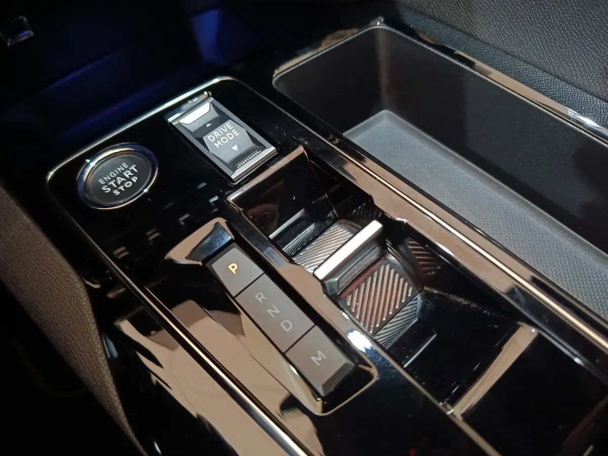 Gros plan sur la console centrale noire brillante du Peugeot 5008 avec bouton démarrage et sélecteur de mode de conduite.