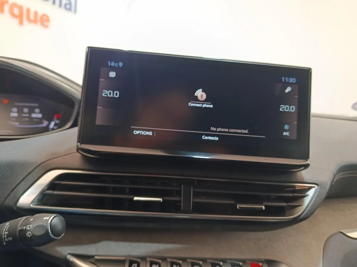 Gros plan sur l’écran tactile central noir du tableau de bord du Peugeot 5008 bleu, affichant la connexion Bluetooth.