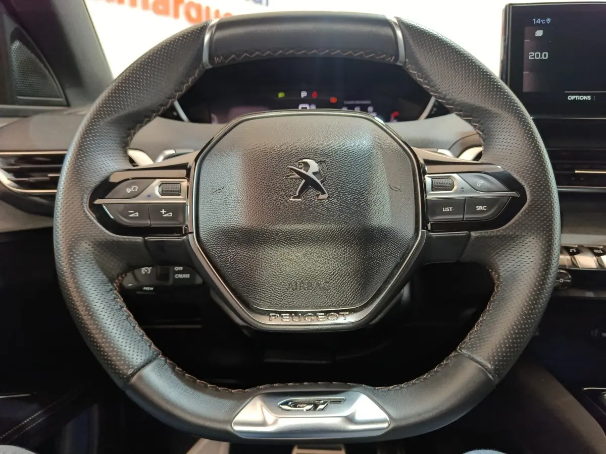 Vue rapprochée du volant cuir noir du Peugeot 5008 GT 2023, avec commandes intégrées et logo central.