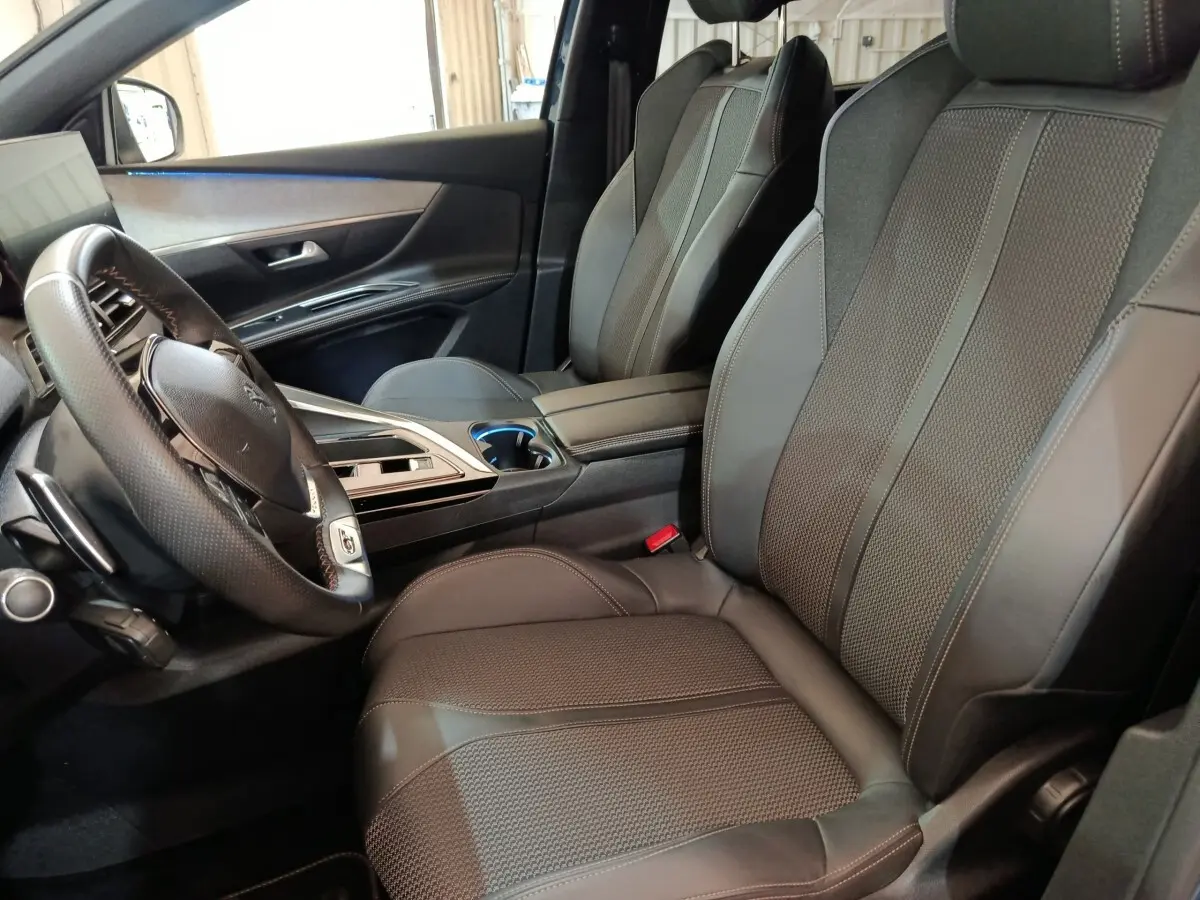 Vue intérieure côté conducteur du Peugeot 5008 2023, sièges en cuir noir et volant multifonctions en cuir.