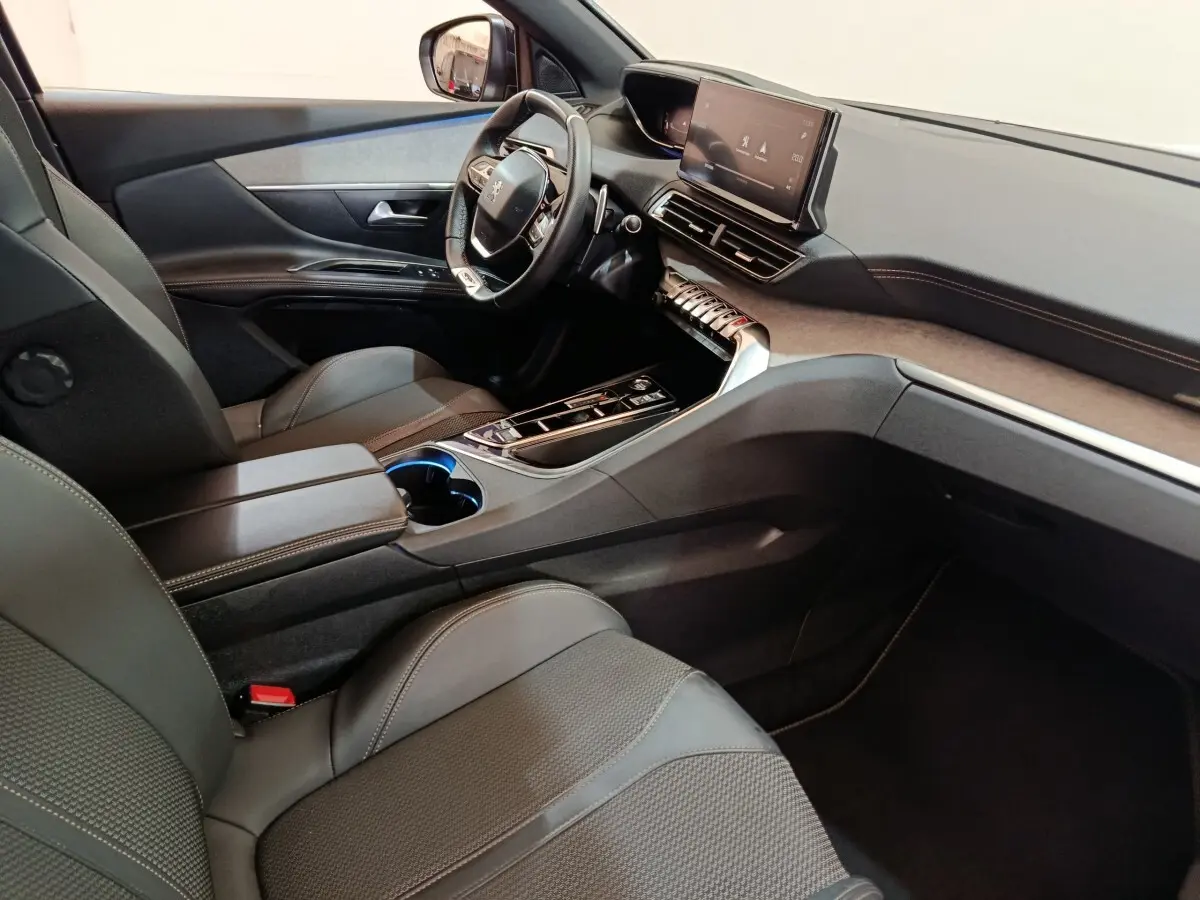 Intérieur Peugeot 5008 GT 2023 vu côté conducteur, tableau de bord moderne avec écran tactile et volant cuir noir.
