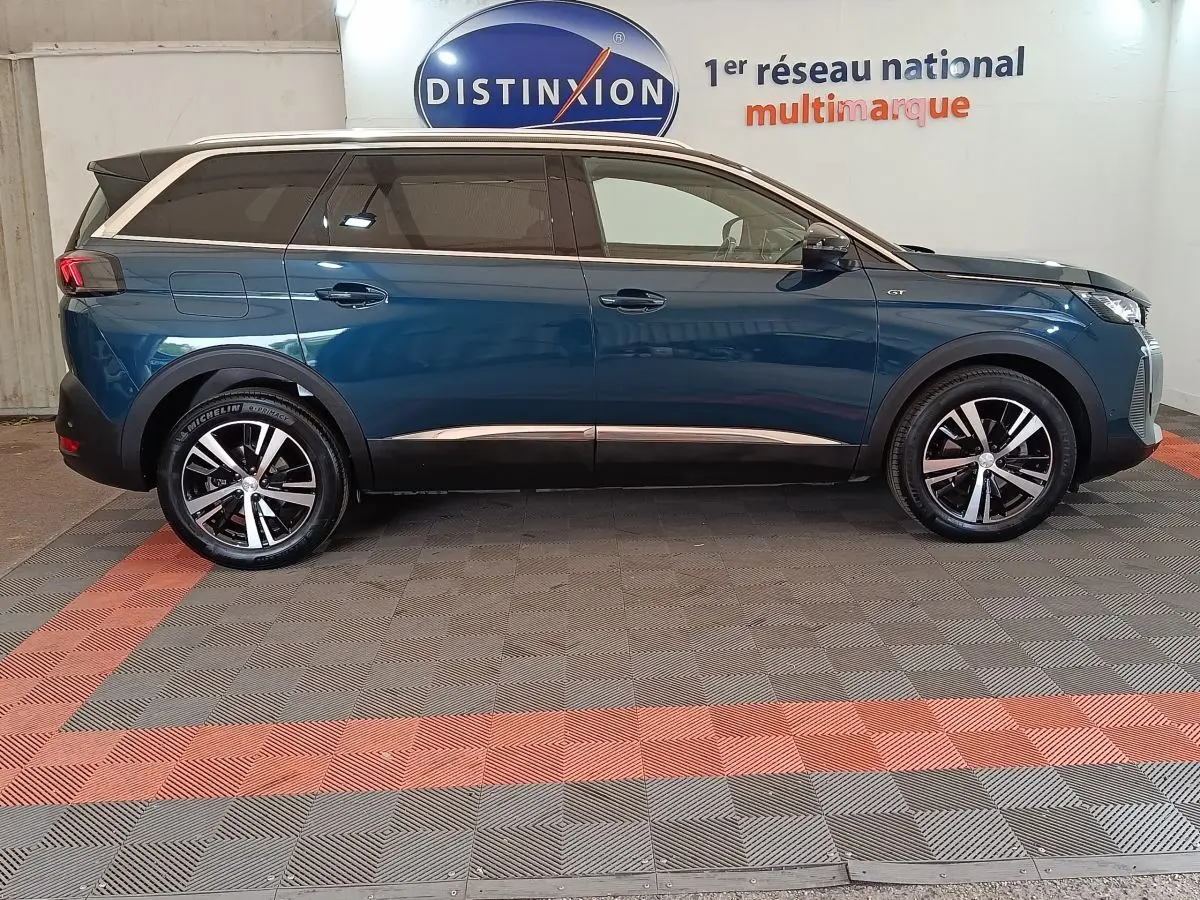 Vue de profil côté gauche d’un Peugeot 5008 GT bleu 2023 avec jantes alliage et toit noir.