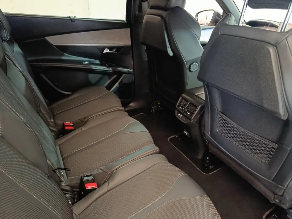 Vue intérieure côté gauche des sièges arrière noirs du Peugeot 5008 2023, avec aérations et rangements au dos des sièges avant.