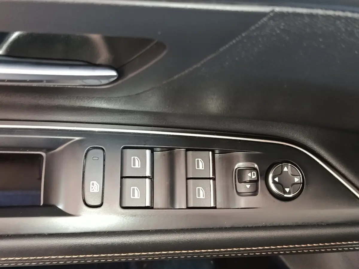 Gros plan sur les commandes de lève-vitres et rétroviseurs côté gauche intérieur d’un Peugeot 5008 bleu 2023.