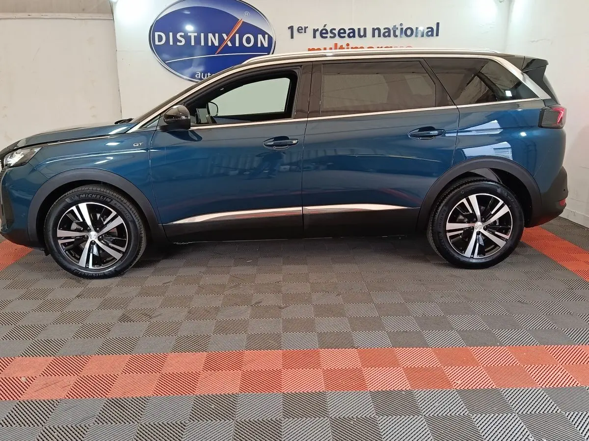 Vue de profil côté gauche d’un Peugeot 5008 GT bleu 2023 avec jantes alliage et toit noir.