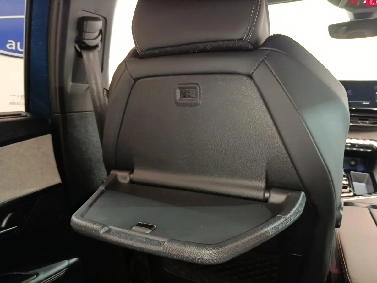 Détail de la tablette rabattable noire sur le dossier du siège avant droit du Peugeot 5008 GT bleu 2023.