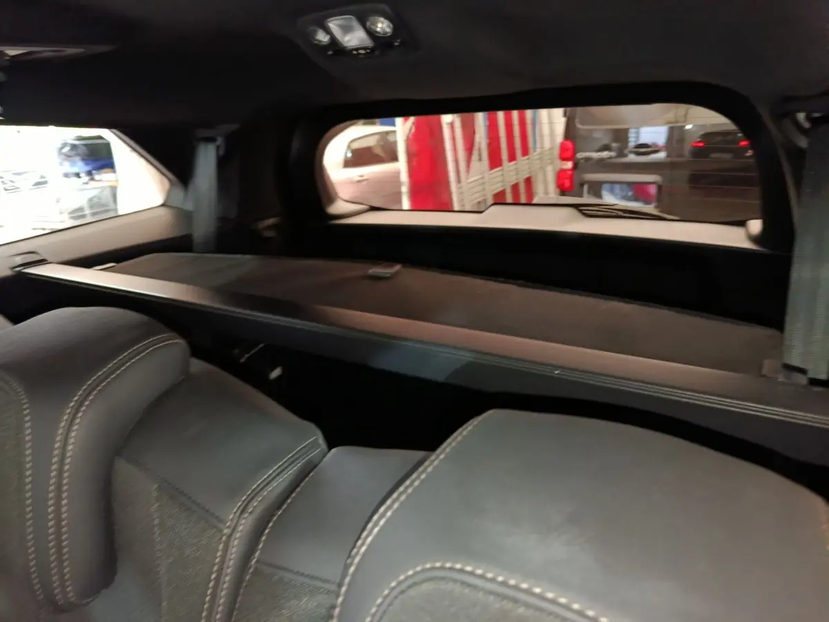Vue intérieure arrière du Peugeot 5008 bleu 2023, montrant les sièges noirs avec surpiqûres et la tablette de coffre.