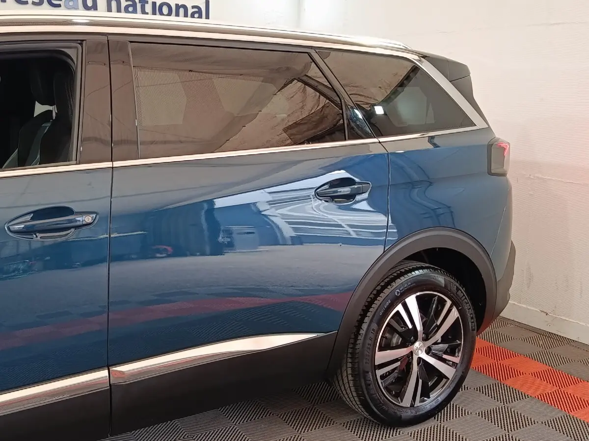 Vue côté droit arrière du Peugeot 5008 bleu 2023 avec jante alliage et vitres teintées.