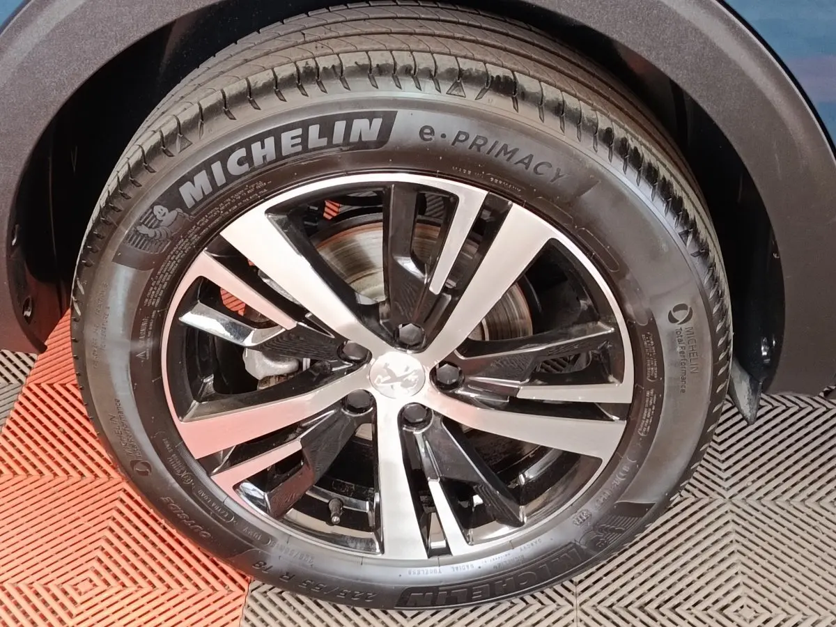 Gros plan sur la jante alliage bicolore et pneu Michelin d’un Peugeot 5008 bleu, côté droit avant.