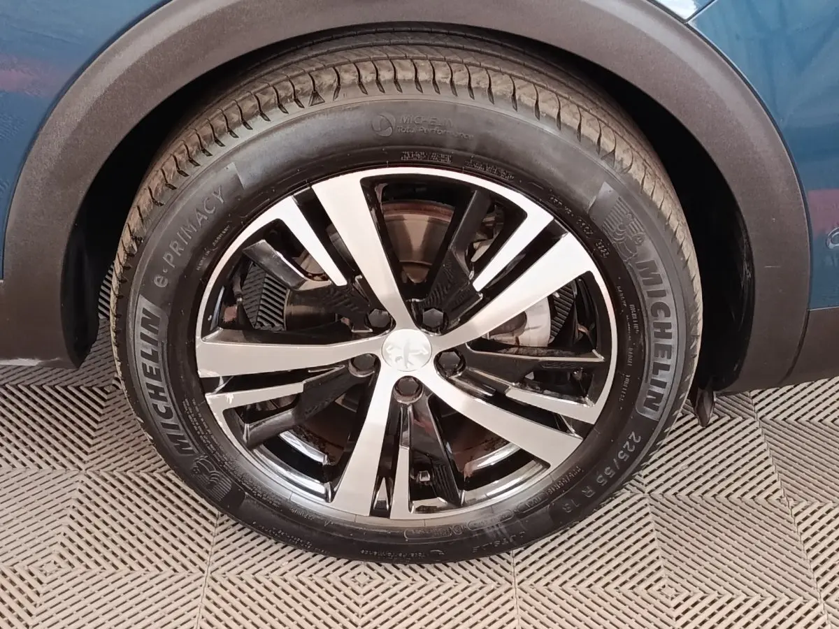 Gros plan sur la roue avant droite du Peugeot 5008 bleu 2023 avec jante alliage bicolore et pneu Michelin.