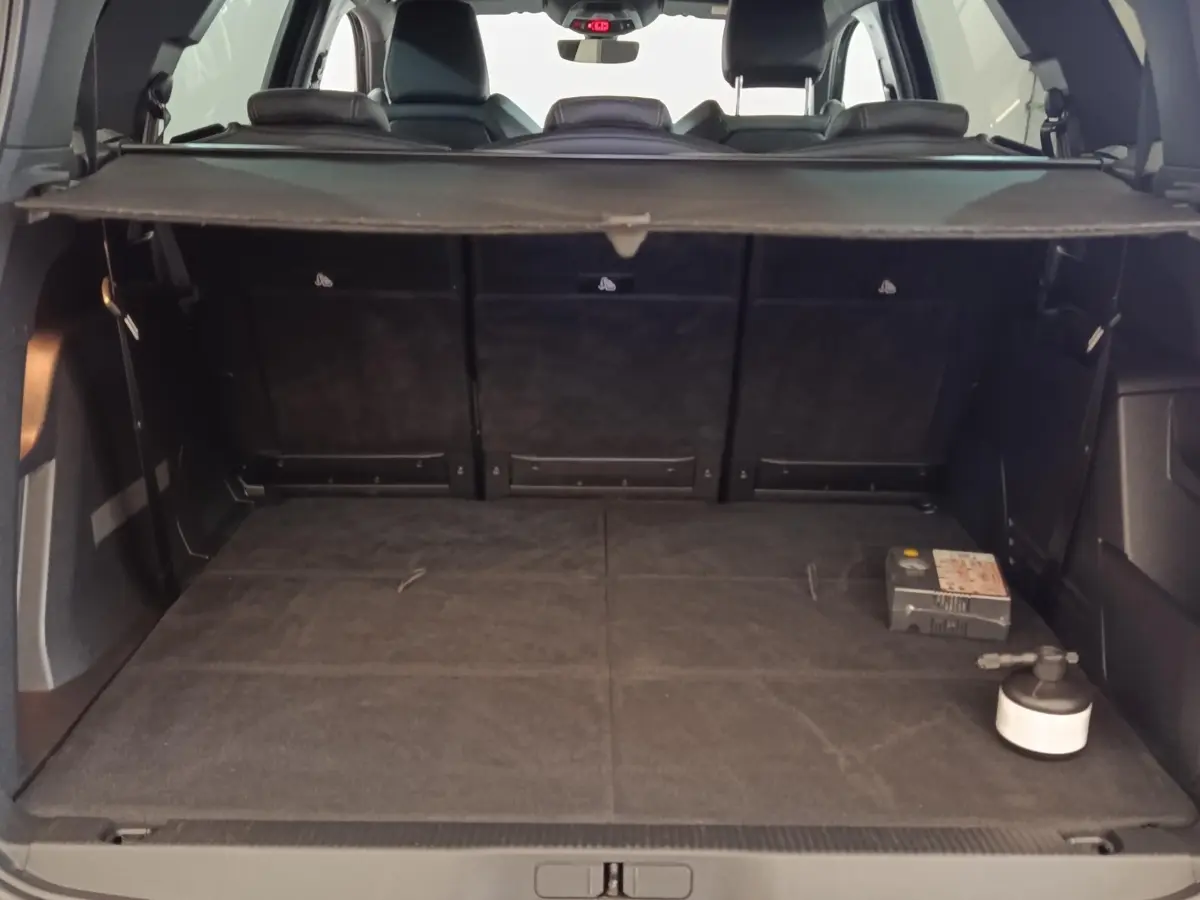 Coffre ouvert vu de l'arrière d'un Peugeot 5008 bleu, avec plancher plat et tablette de séparation noire.