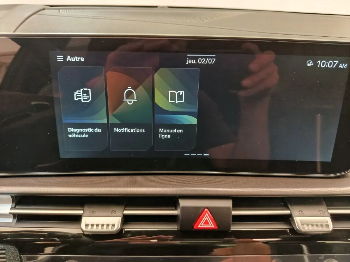 Écran tactile central affichant le menu diagnostic, notifications et manuel en ligne dans un Kia Sportage gris foncé.