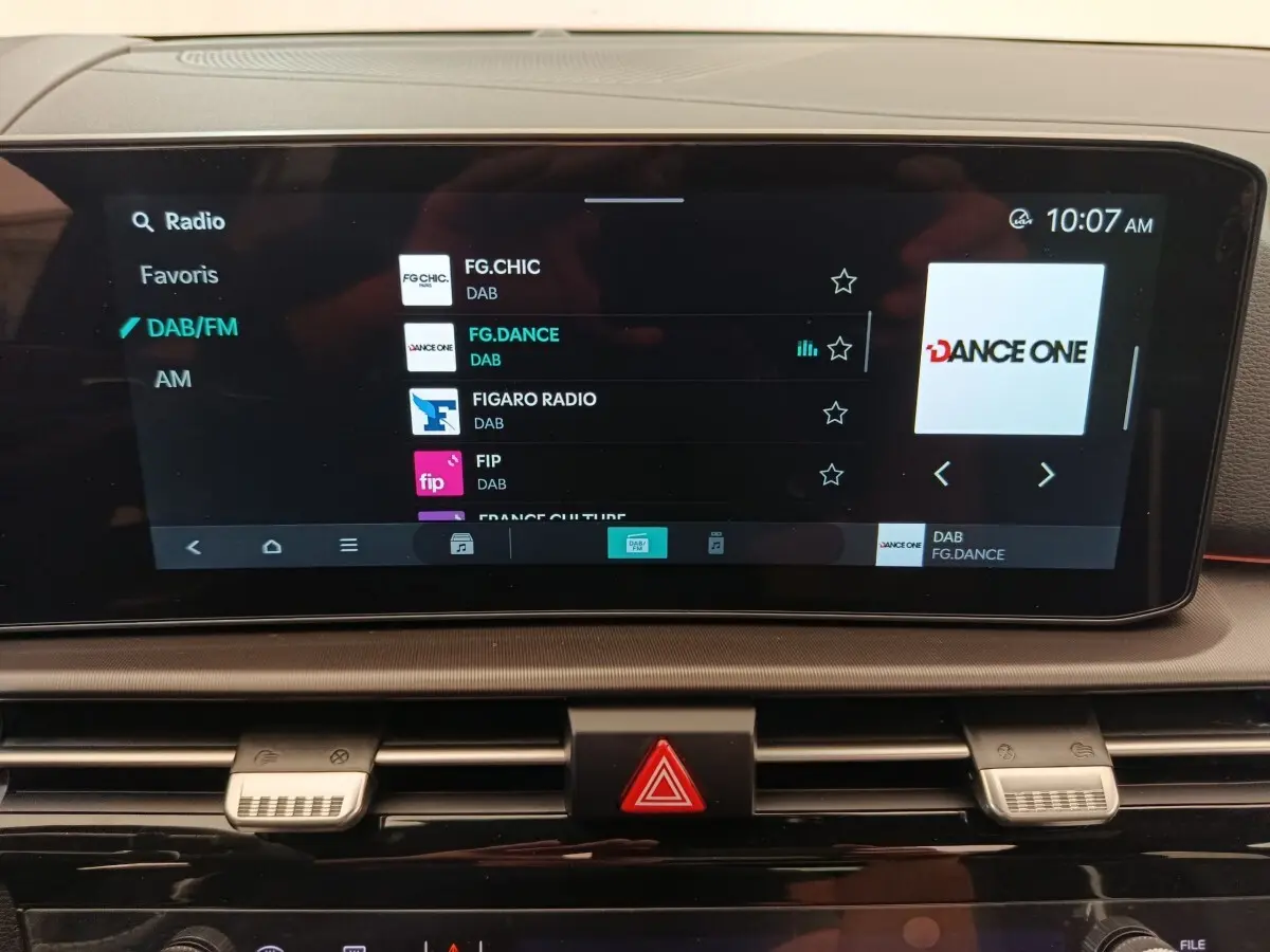 Écran tactile central affichant la radio DAB dans l'habitacle du Kia Sportage gris foncé, vue de face.