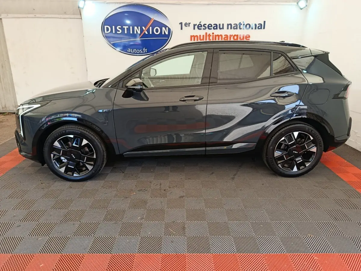 Vue latérale droite du KIA SPORTAGE gris foncé 2026 avec jantes noires au design moderne et toit noir contrasté.