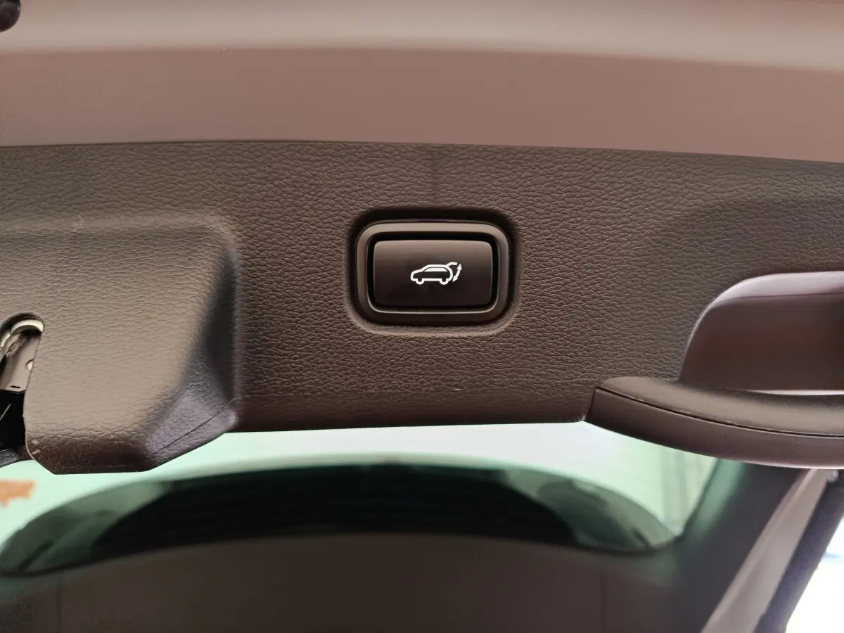 Bouton d'ouverture électrique du coffre sur le bord intérieur du hayon du Kia Sportage gris foncé.