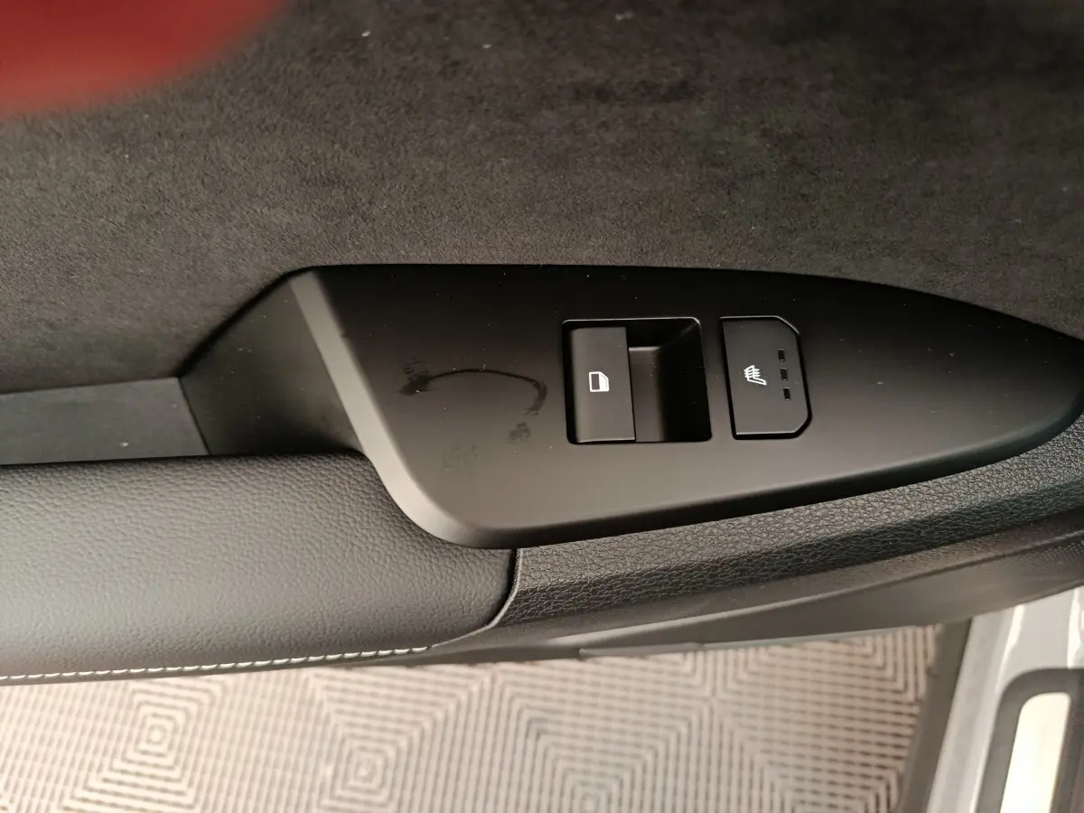 Gros plan sur la commande de verrouillage et siège chauffant côté porte avant d’un Kia Sportage gris foncé.