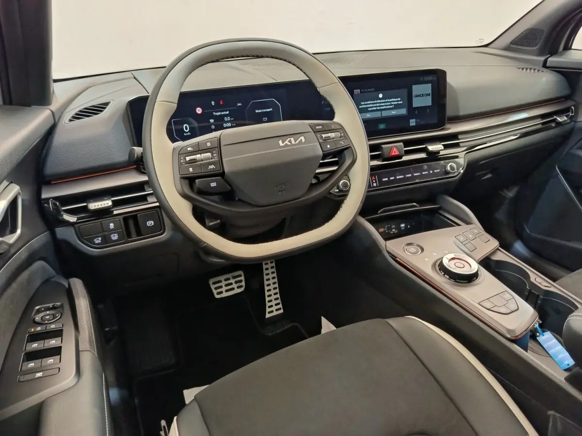 Vue intérieure côté conducteur du tableau de bord et volant bi-ton beige et noir du Kia Sportage gris foncé 2026.