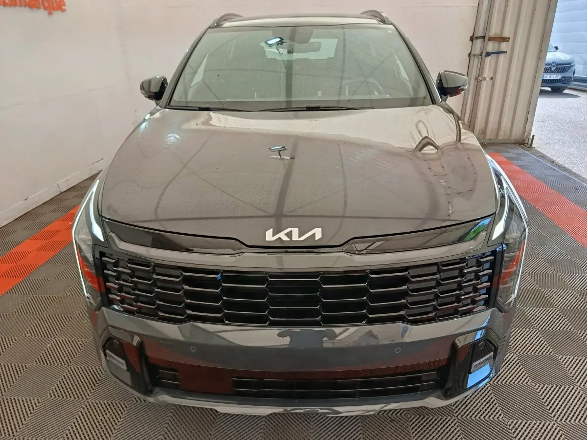 Vue avant d'un KIA Sportage gris foncé avec calandre noire et logo KIA moderne sur le capot.