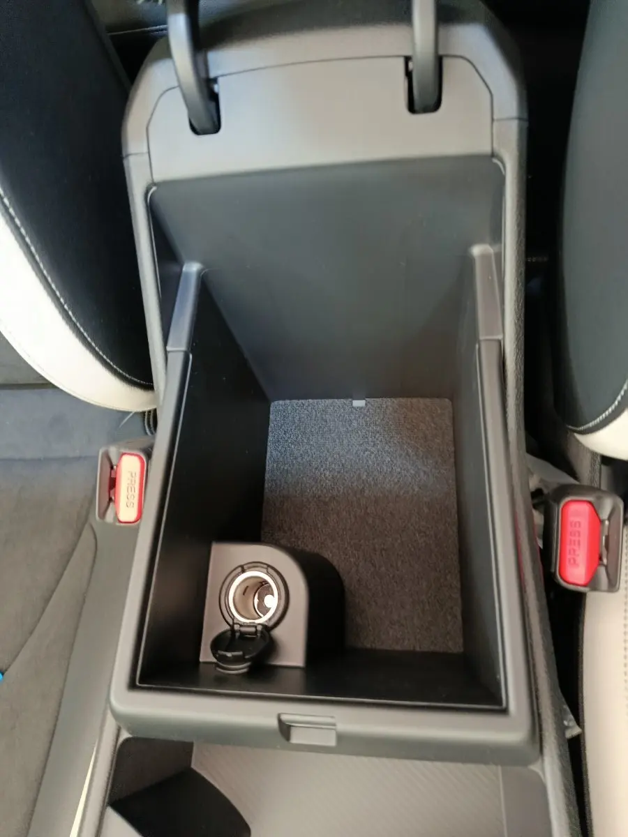 Vue plongeante sur la console centrale ouverte du Kia Sportage 2026, intérieur noir avec prise allume-cigare visible.