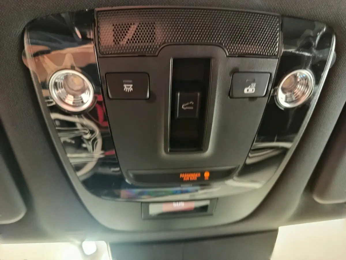 Plafonnier intérieur noir brillant du Kia Sportage 2026 avec commandes d'éclairage et détecteur passager allumé.