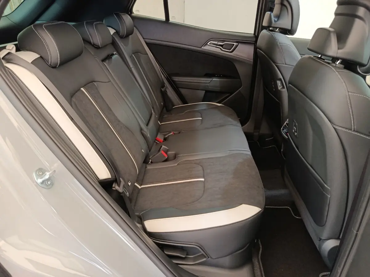 Vue intérieure côté gauche des sièges arrière noirs avec surpiqûres blanches du Kia Sportage gris foncé 2026.