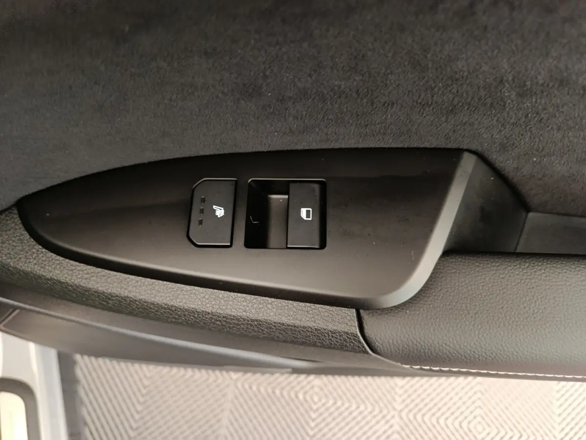 Gros plan sur les commandes de siège chauffant et de verrouillage sur la porte côté gauche du Kia Sportage gris foncé 2026.