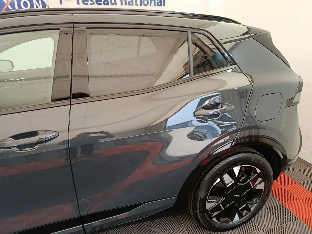 Vue latérale arrière droite du Kia Sportage gris foncé, mettant en valeur la jante noire au design moderne.
