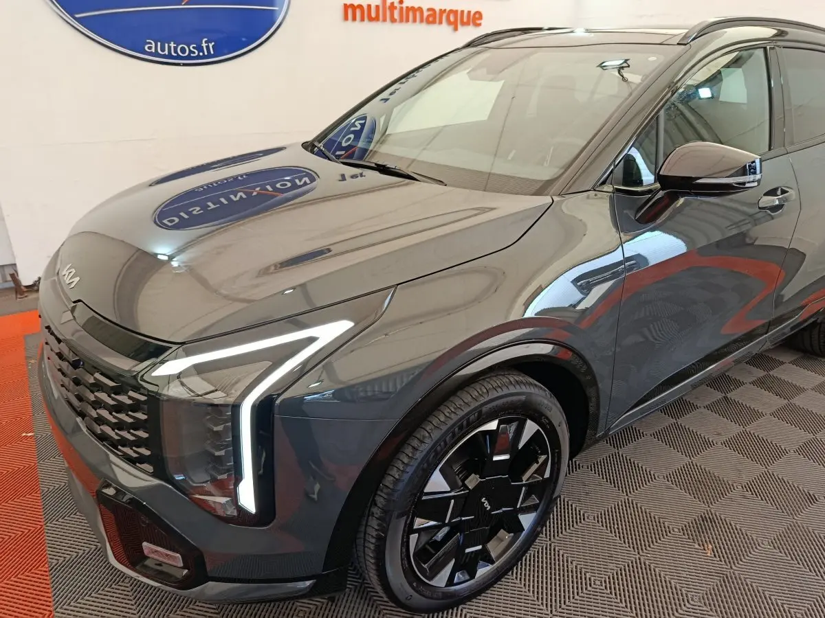 Vue 3/4 avant droit du KIA Sportage gris foncé avec phares LED en forme de L et jantes noires stylisées.