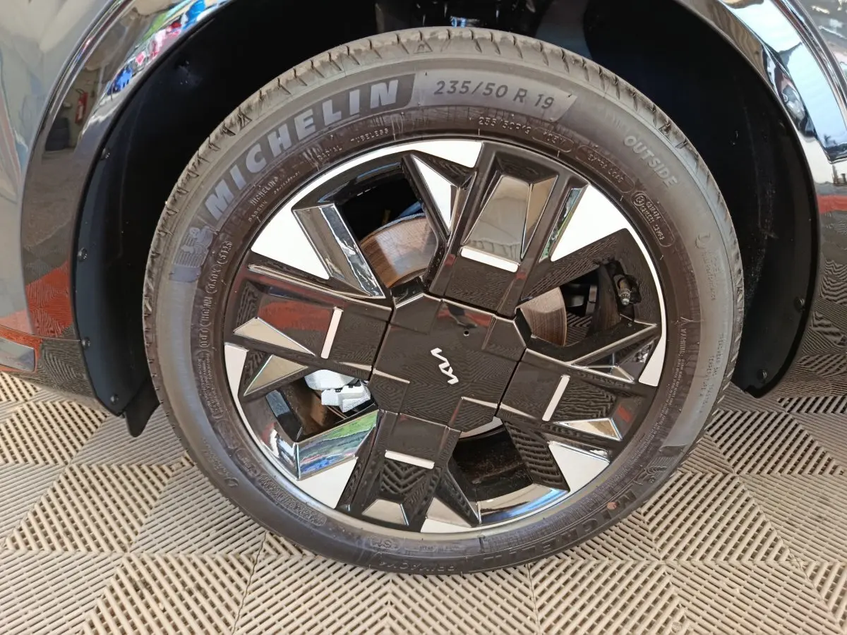 Gros plan sur la roue avant droite du KIA SPORTAGE gris foncé avec jante noire et argentée au design géométrique.