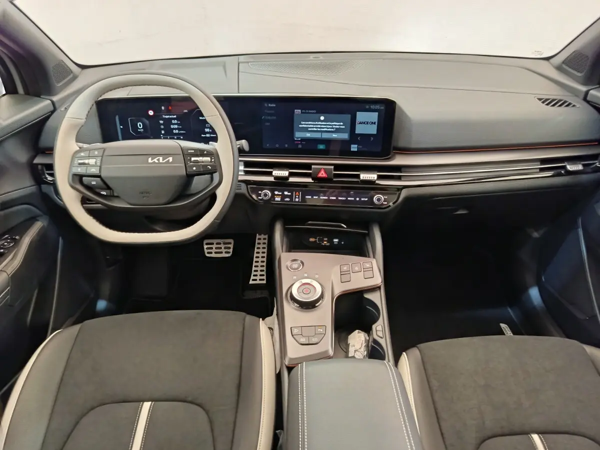 Vue intérieure avant du Kia Sportage gris foncé, tableau de bord avec écran tactile large et volant multifonctions.