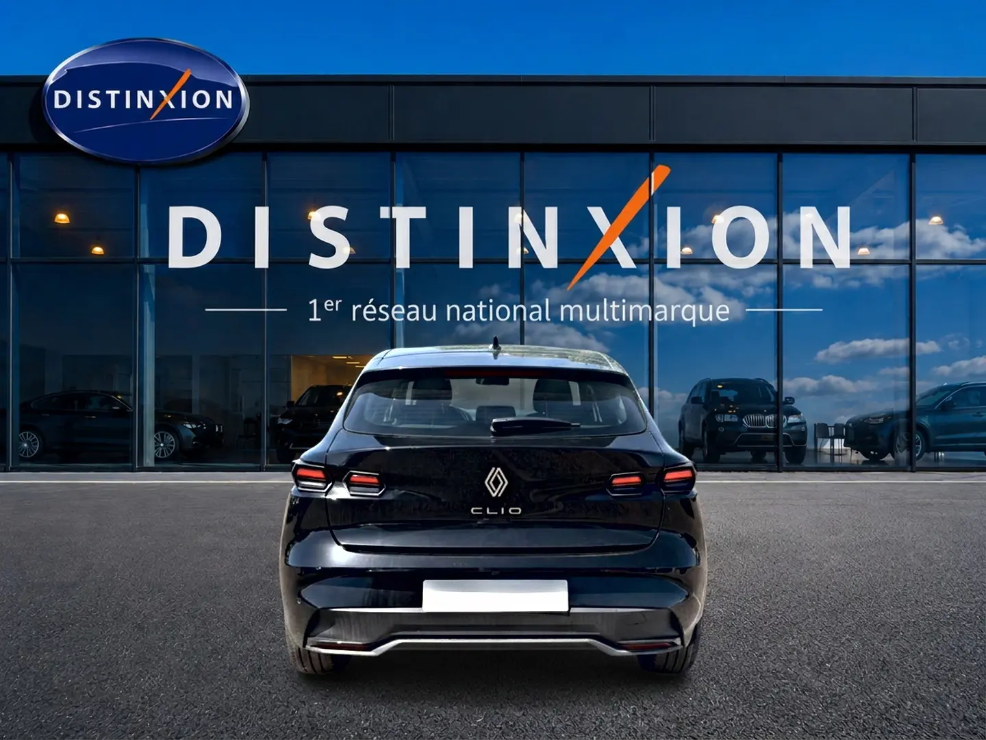 Vue arrière d'une Renault Clio VI noire garée devant une vitrine avec logo Distinxion en arrière-plan.
