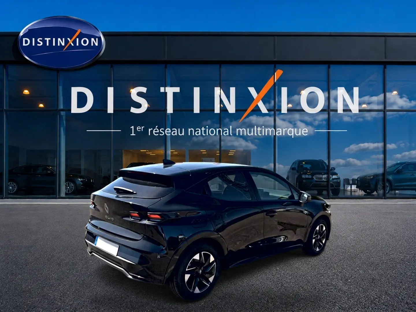 Vue 3/4 arrière droite d'une Renault Clio VI noire garée devant une vitrine avec logo Distinxion.