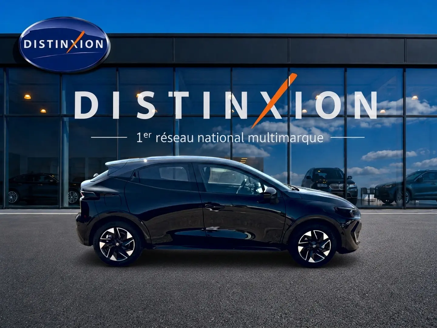 Profil côté gauche d'une Renault Clio VI noire 2026 avec jantes alliage, devant une vitrine Distinxion.