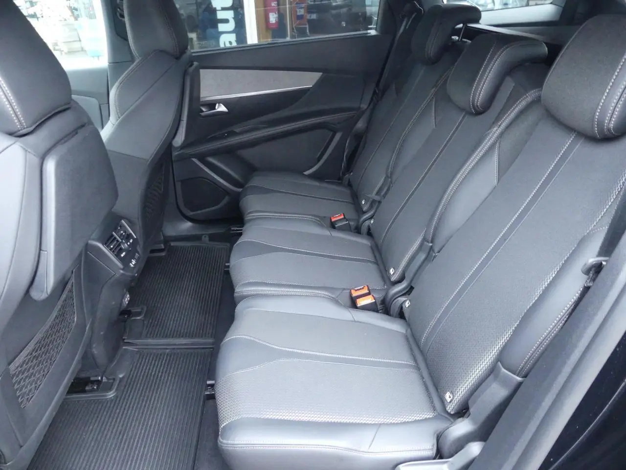 Vue latérale des trois sièges arrière indépendants en cuir noir du Peugeot 5008 GT 2023, avec accoudoirs et ceintures visibles.