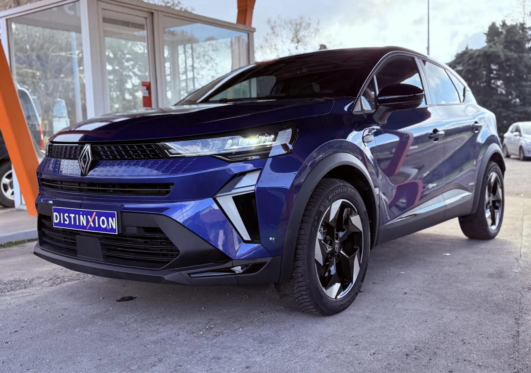 Renault Captur E-Tech hybride 2025 bleu Iron Metal avec toit noir, vu en 3/4 avant droit sous abri.