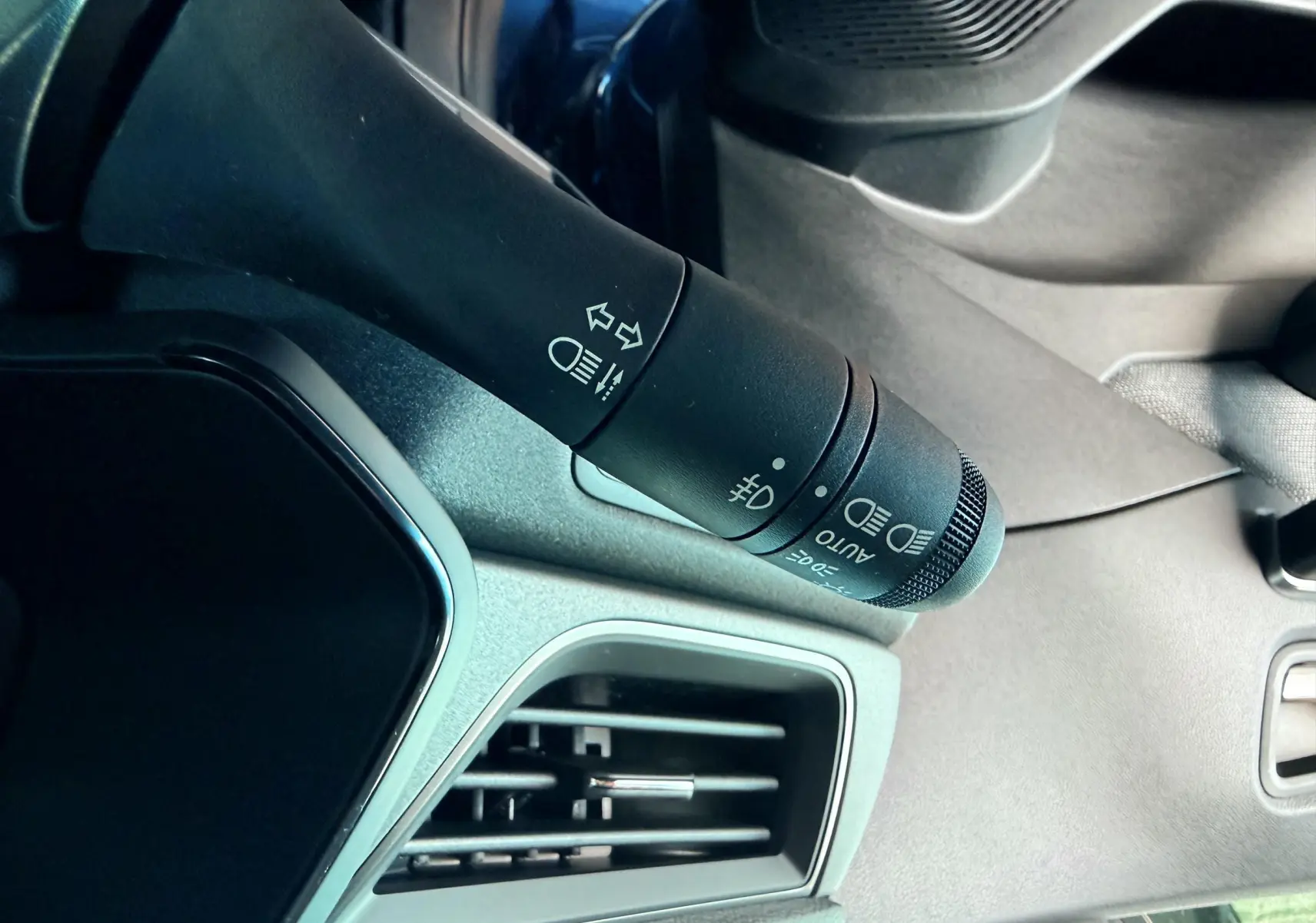 Gros plan sur la commande des phares et clignotants à gauche du volant dans l'habitacle du Renault Captur bleu 2025.