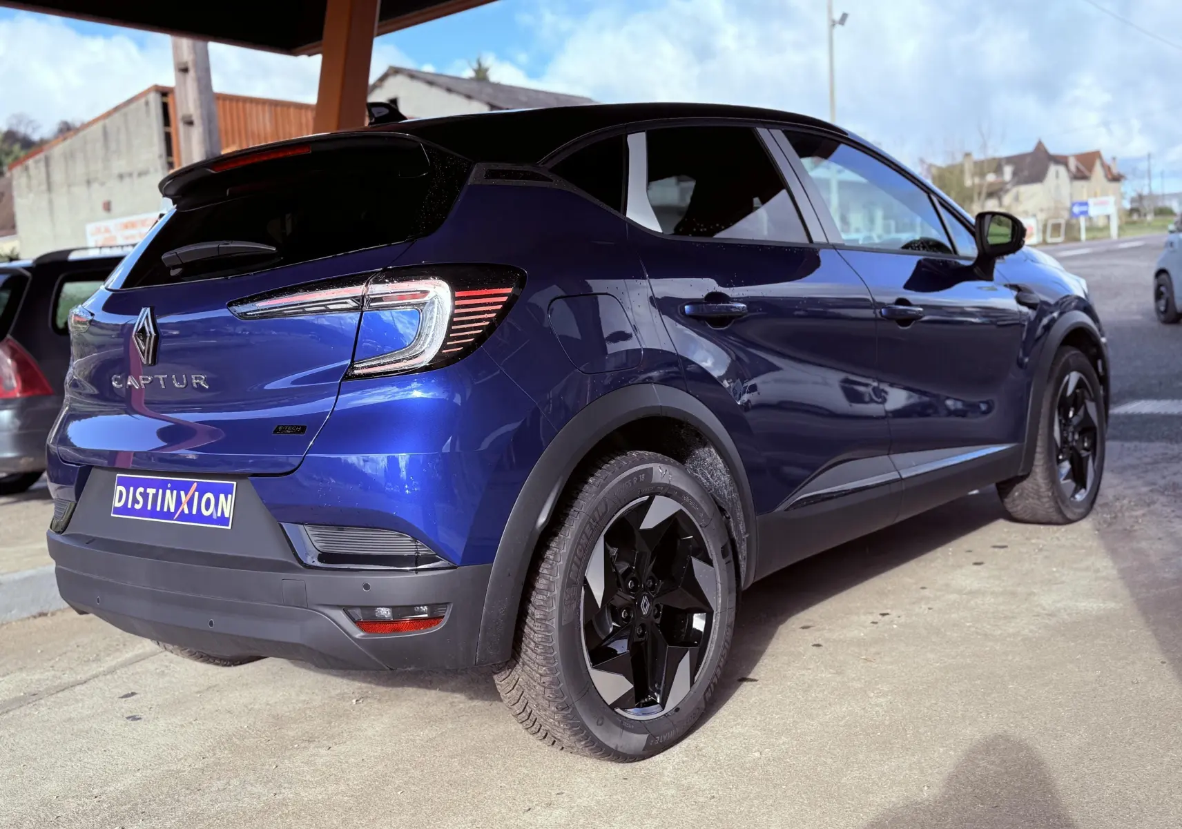 Renault Captur E-Tech hybride 2025 bleu Iron Metal avec toit noir, vue 3/4 arrière côté droit, jantes noires distinctives.