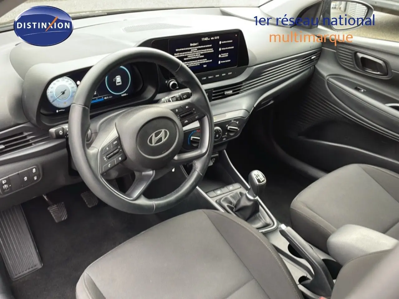 Intérieur noir de la Hyundai i20 2025, vue côté conducteur, volant cuir multifonction et tableau de bord digital.