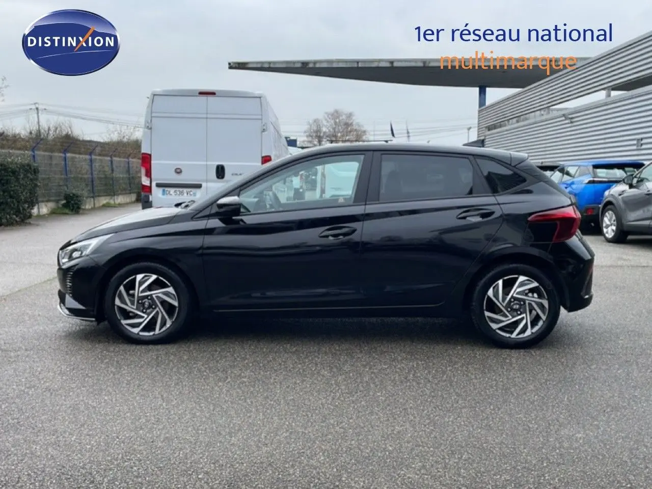 Profil côté gauche d'une Hyundai i20 noire Phantom Metal 2025 garée sur un parking extérieur.