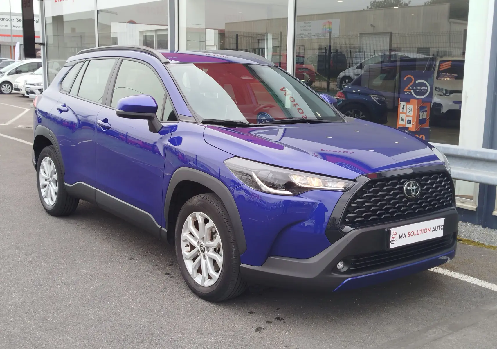 Toyota Corolla Cross bleu cosmique vue en 3/4 avant droit, avec calandre noire et jantes alliage argentées.