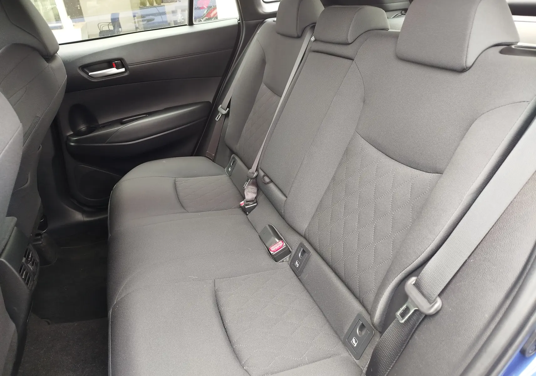 Vue intérieure de la banquette arrière grise du Toyota Corolla Cross 2024, côté droit avec ceinture de sécurité visible.