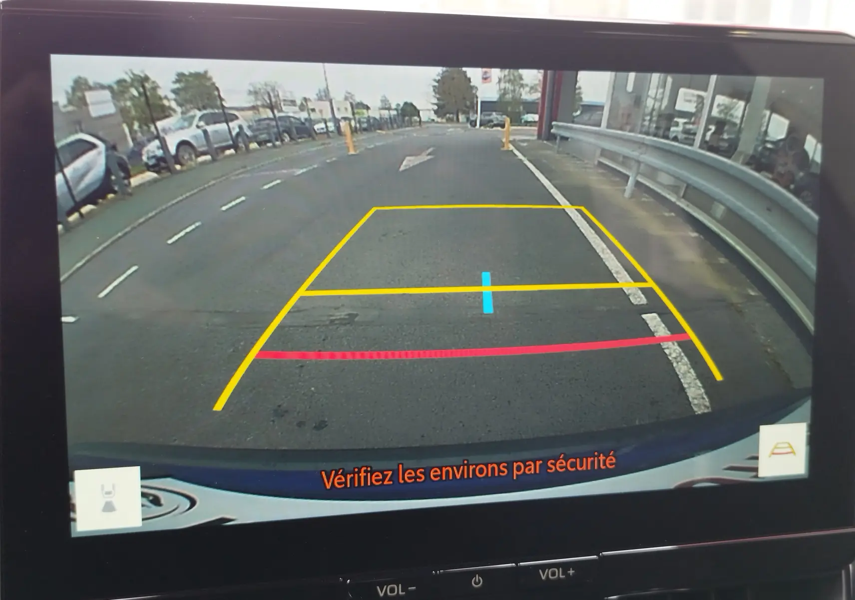 Vue de la caméra de recul de la Toyota Corolla Cross 2024, affichant les lignes de guidage sur un parking urbain.