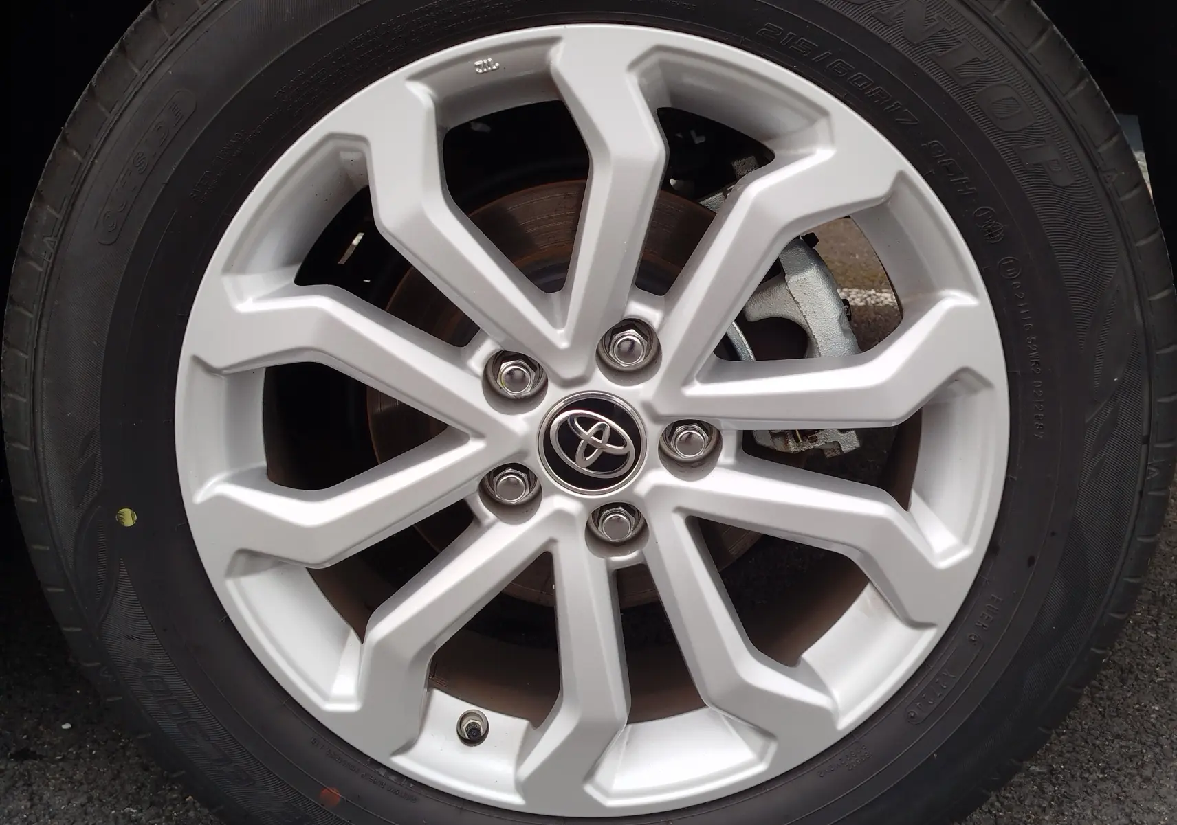 Gros plan sur la jante alliage argentée avec logo Toyota au centre du Toyota Corolla Cross 2024 Bleu Cosmique.