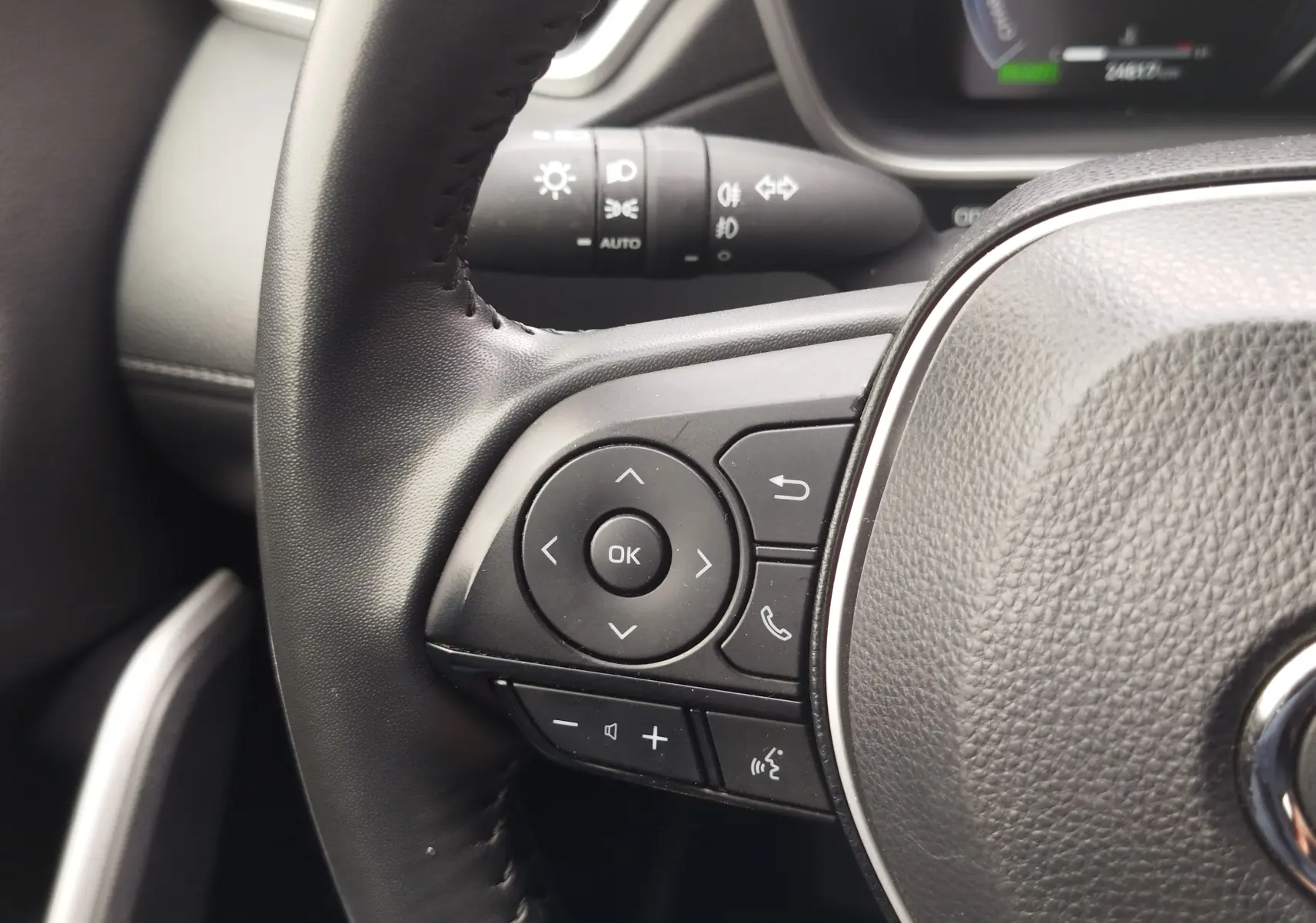 Gros plan sur les commandes multifonctions à gauche du volant en cuir noir du Toyota Corolla Cross 2024.