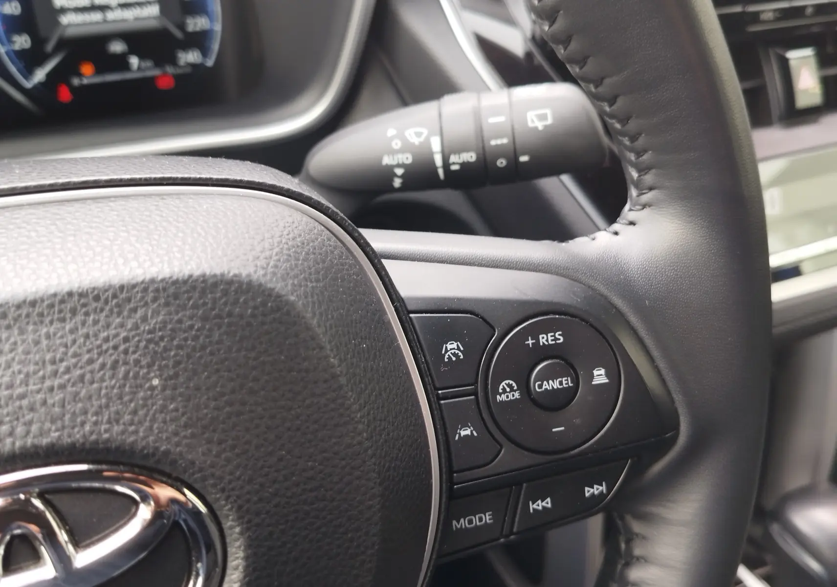 Gros plan sur le volant noir de la Toyota Corolla Cross 2024, montrant les commandes de régulateur et d’aide à la conduite.