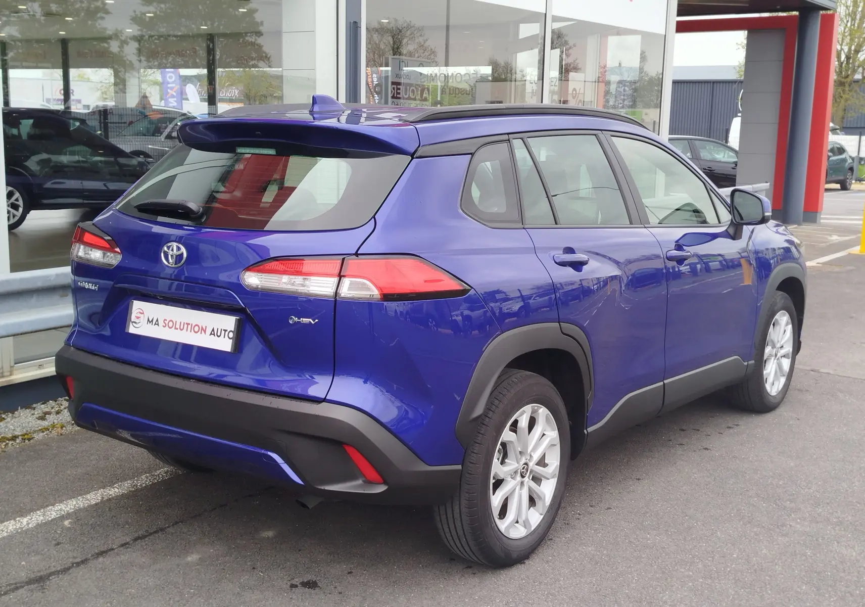 Vue 3/4 arrière droite d'un Toyota Corolla Cross 1.8l 140h Dynamic bleu cosmique avec jantes alliage et détails noirs contrastants.