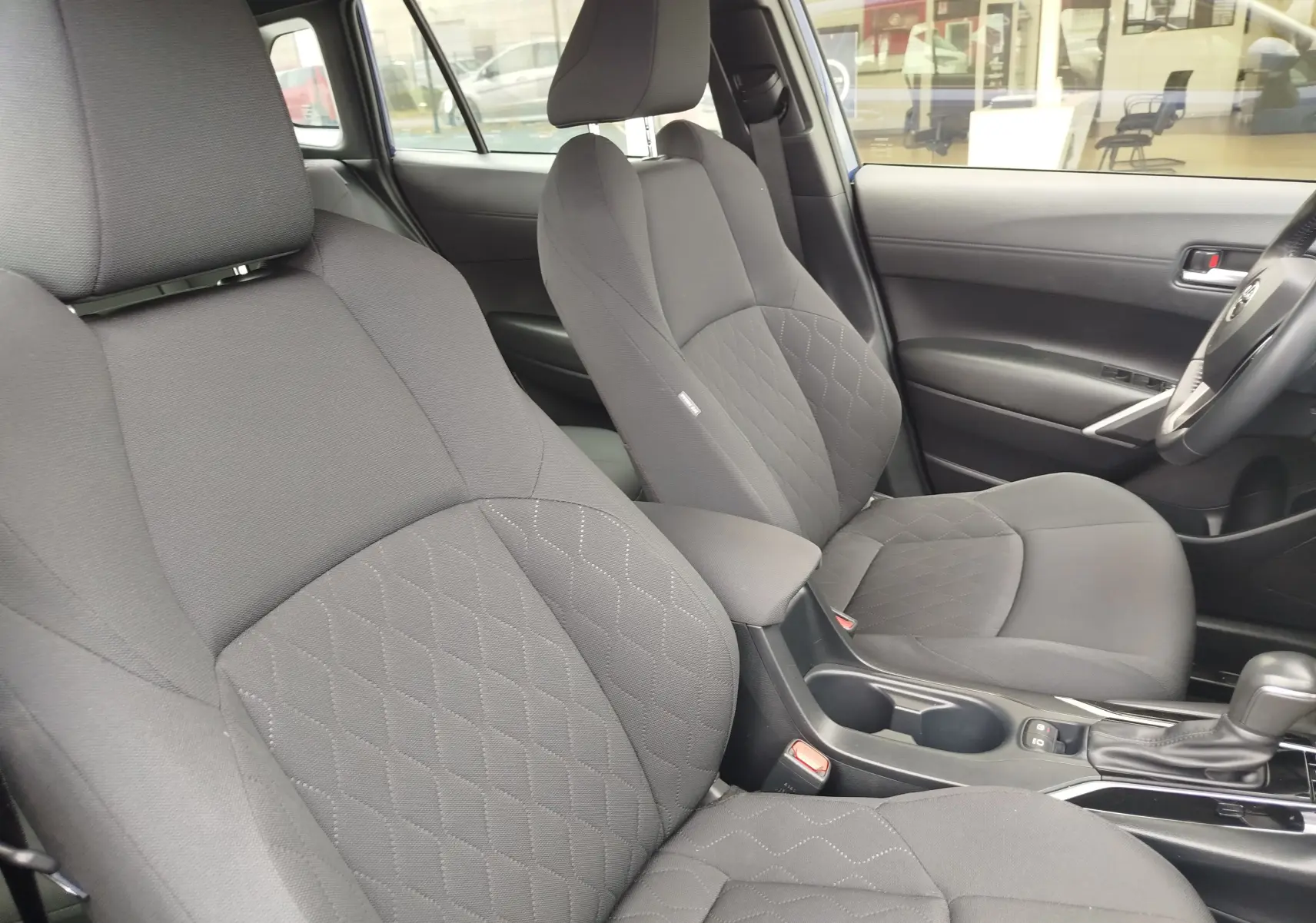 Vue intérieure côté droit des sièges avant gris foncé avec surpiqûres en losange du Toyota Corolla Cross 2024.