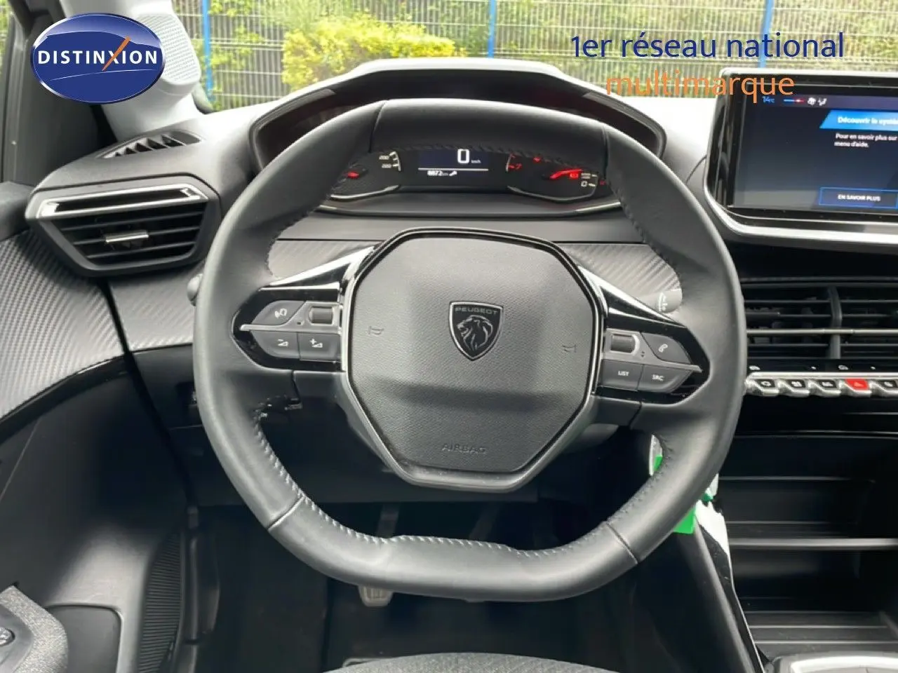 Vue rapprochée du volant cuir multifonction noir de la Peugeot 208 1.2 100CH STYLE, avec tableau de bord digital en arrière-plan.